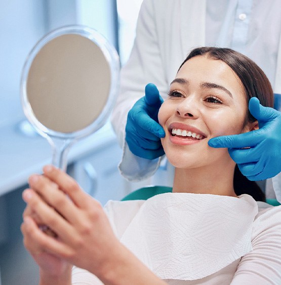 Patient smiling at reflection in handheld mirror