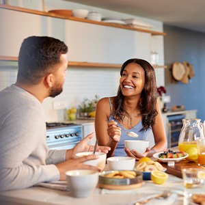 Couple smiling at each other while eating in kitchen