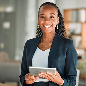 Woman smiling while holding tablet in office