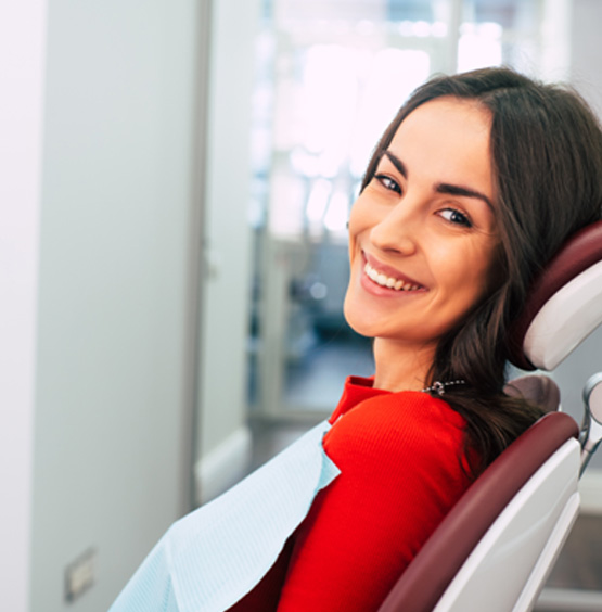 Female dental patient in red shirt smiling while sitting in chair