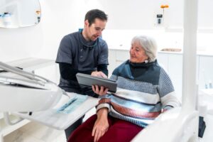 Dentist and patient looking at tablet during dental implant consultation