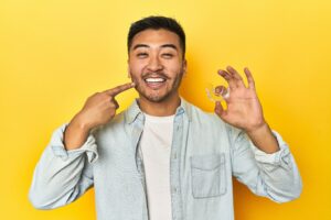 Adult man smiling and holding Invisalign clear aligner.